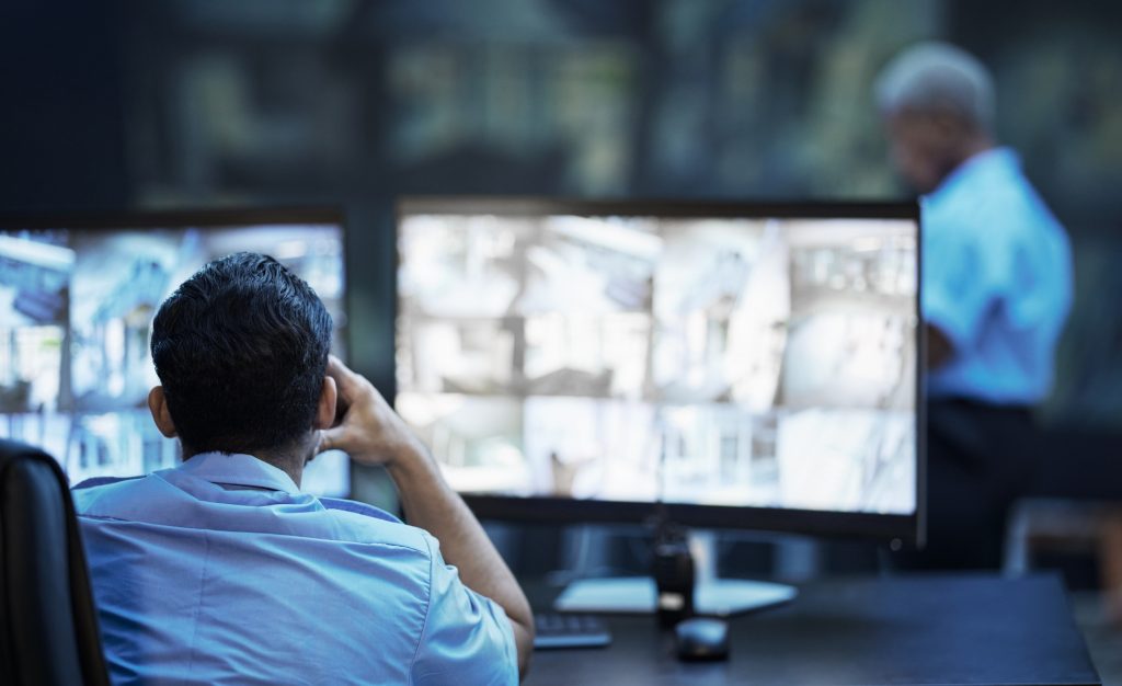 Security guard in control room, man checking cctv screen in surveillance office for building safety | Bursa Genel Güvenlik Sistemleri Security guard in control room, man checking cctv screen in surveillance office for building safety